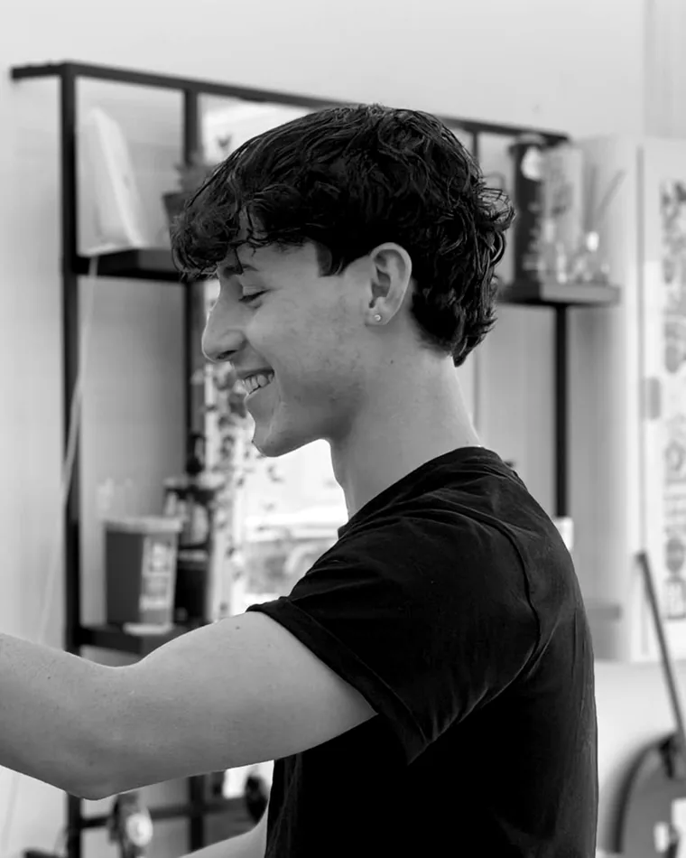 Jean, barber at Mus Cuts, smiling while cutting a client's hair